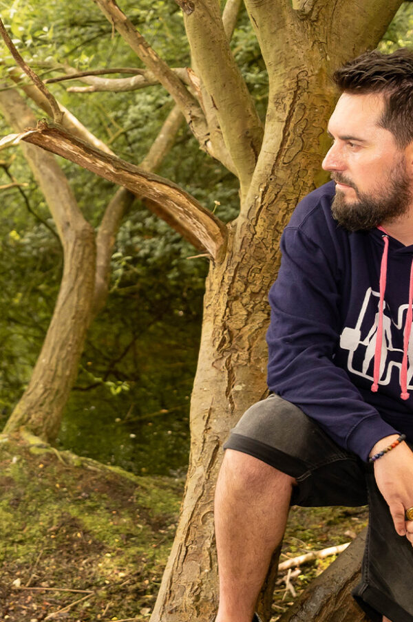 Co-Founder of Buds Fitness and Founder Of Together We Lift Sat in a tree, in his Navy Mental Health Hoodie looking out on a restful lake in Cambridgeshire