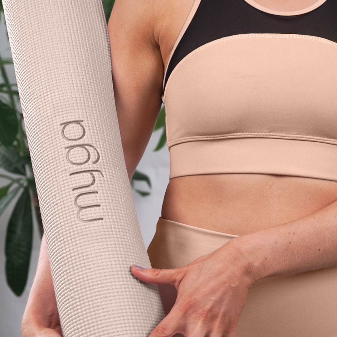 Person carrying a rolled pink Myga yoga mat