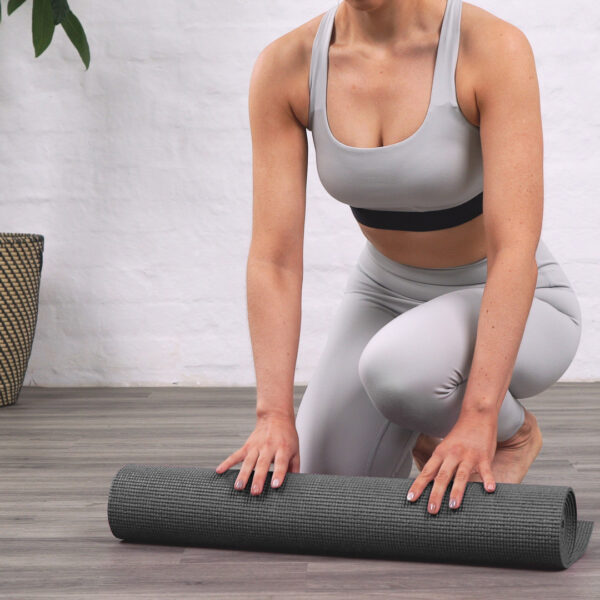 A lady rolling up her black yoga mat by Myga