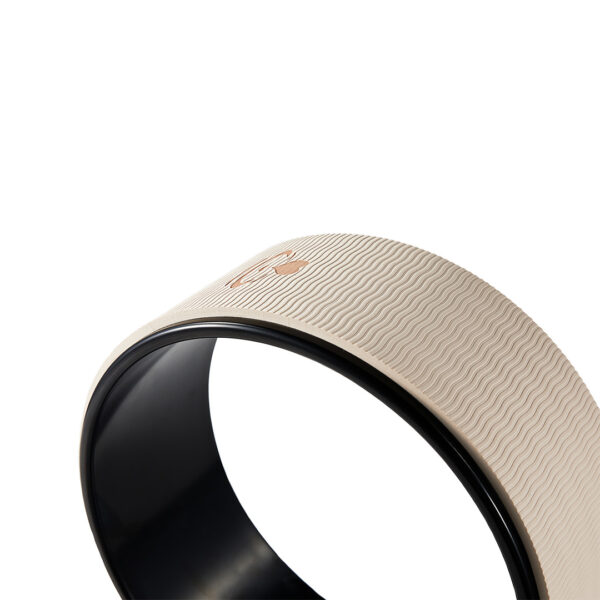 Close-up of beige yoga wheel surface showing textured non-slip TPE padding.