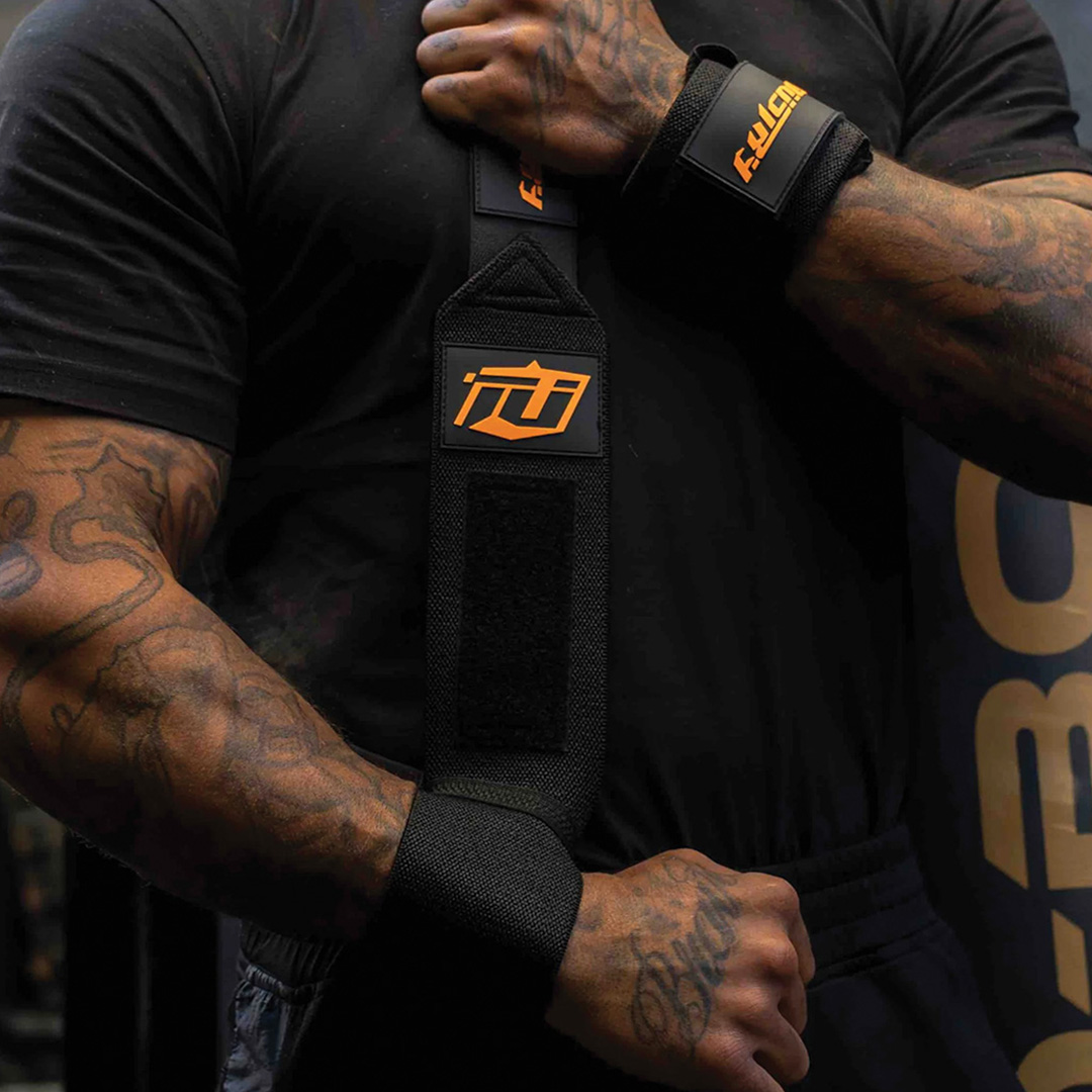 Strength Athlete wrapping his no thumb loop black wrist straps with orange detailing