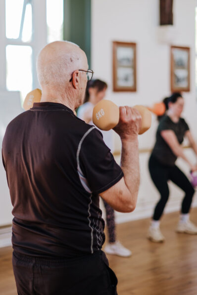 Participant lifting dumbbells during a FitFactory group fitness class at the Old School Hall in Sawtry.