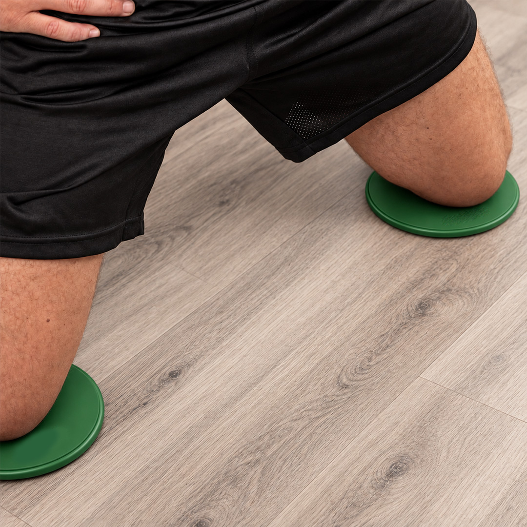 Green gliding discs used for controlled home workout exercises
