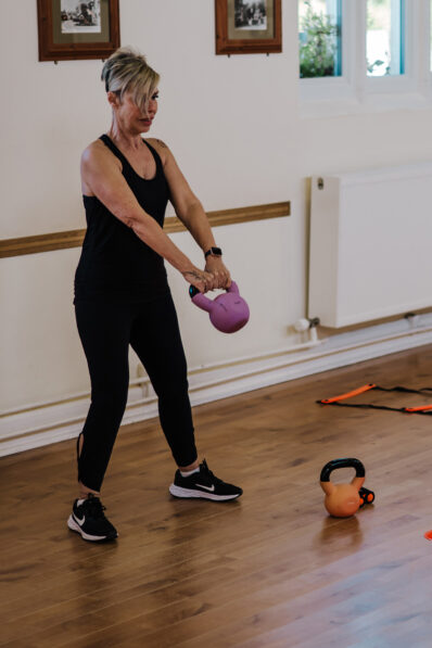 Woman performing a kettlebell swing during a functional fitness class at FitFactory in Sawtry.